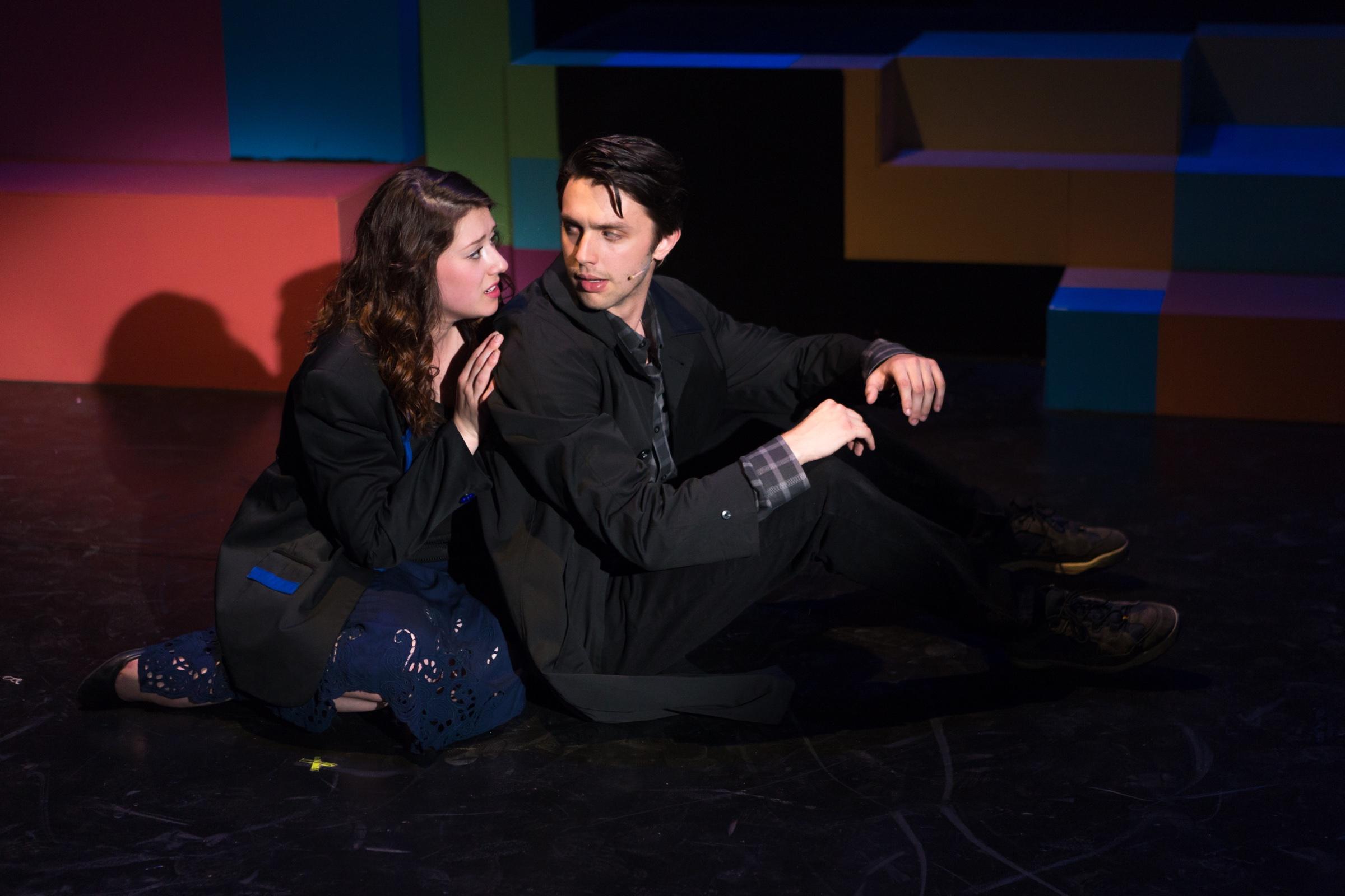 Shane Lonergan as J.D. sitting on the floor beside Veronica against the colour-block set of Heathers