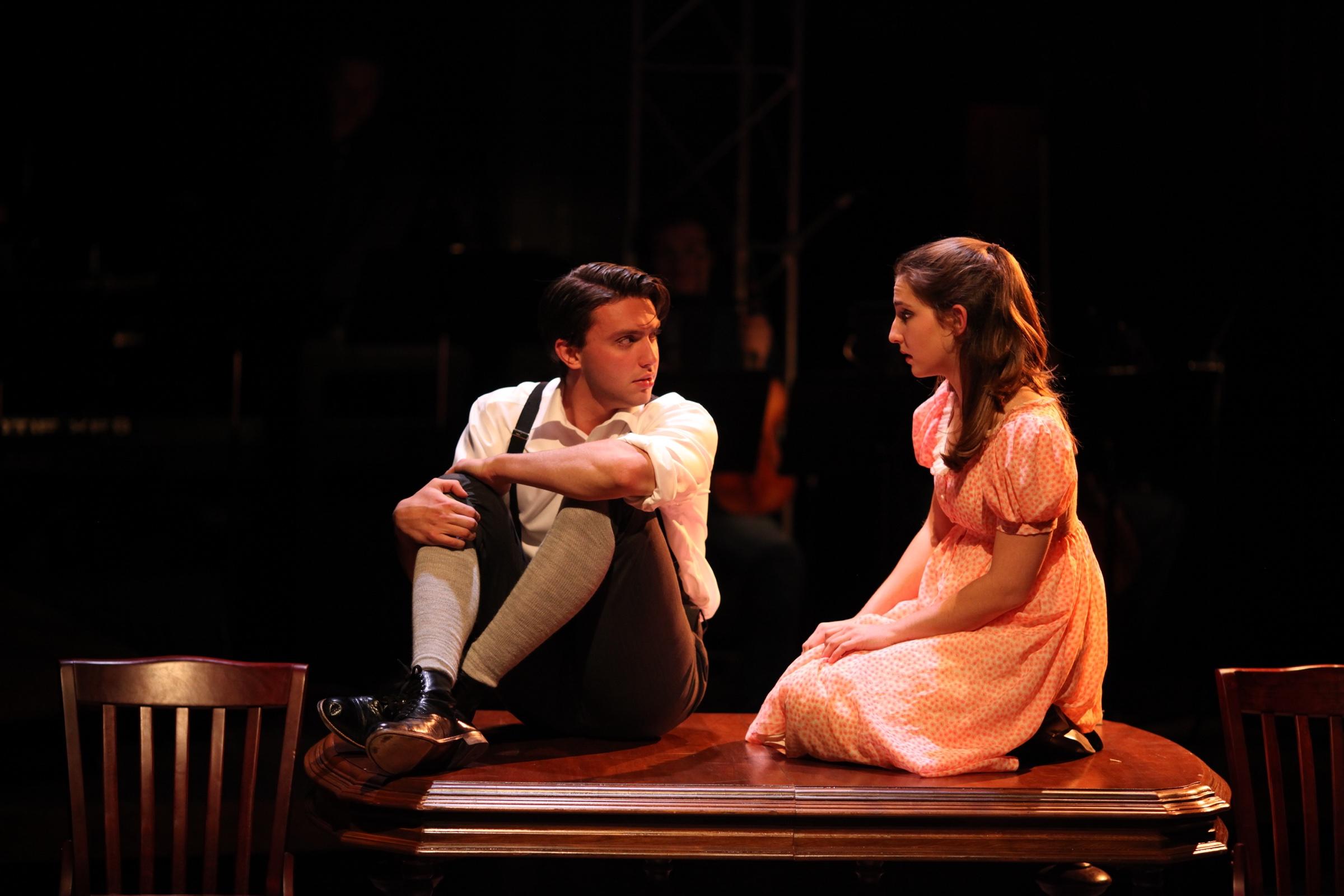 Shane Lonergan as Melchior seated on a table opposite Wendla