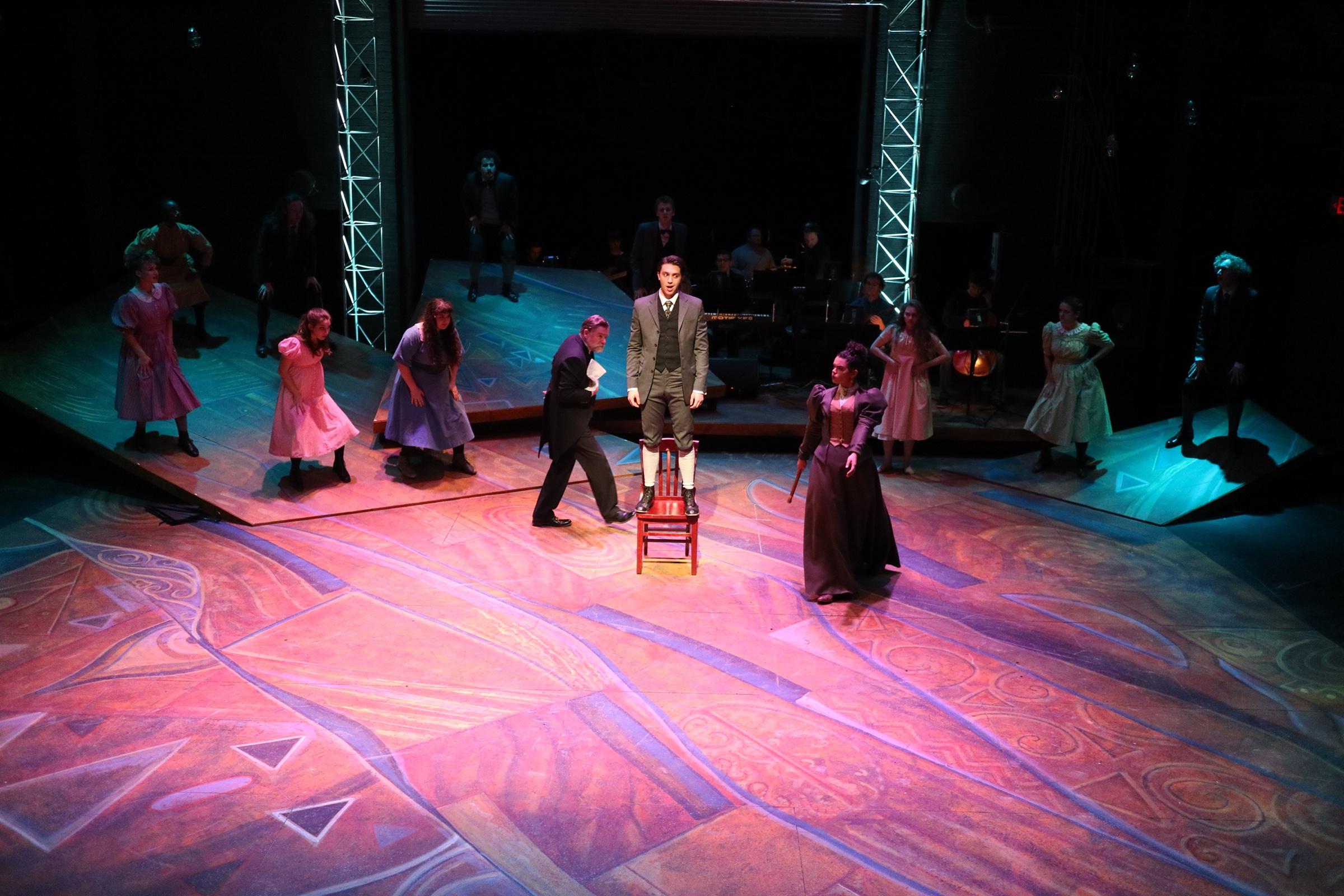 A wide view of the Spring Awakening stage, the company spread across its painted floor
